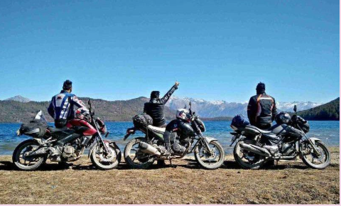 Motorcycle riders enjoying a scenic Rara Lake view with Himalayan mountains in the background