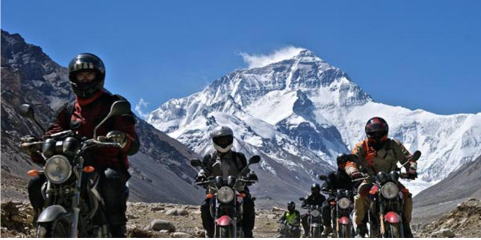 Motorbike tour group riding in Nepal Himalayas with stunning Mount Annapurna backdrop