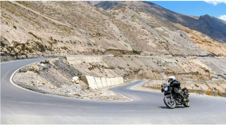 Motorcycle rider on Royal enfield himalayan cornering around Lower Mustan